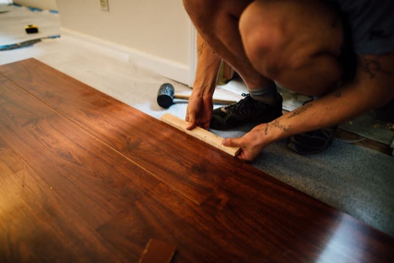 Flooring fitter on his knees laying laminate boards