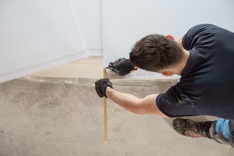 Flooring fitter measuring the floor before cutting boards