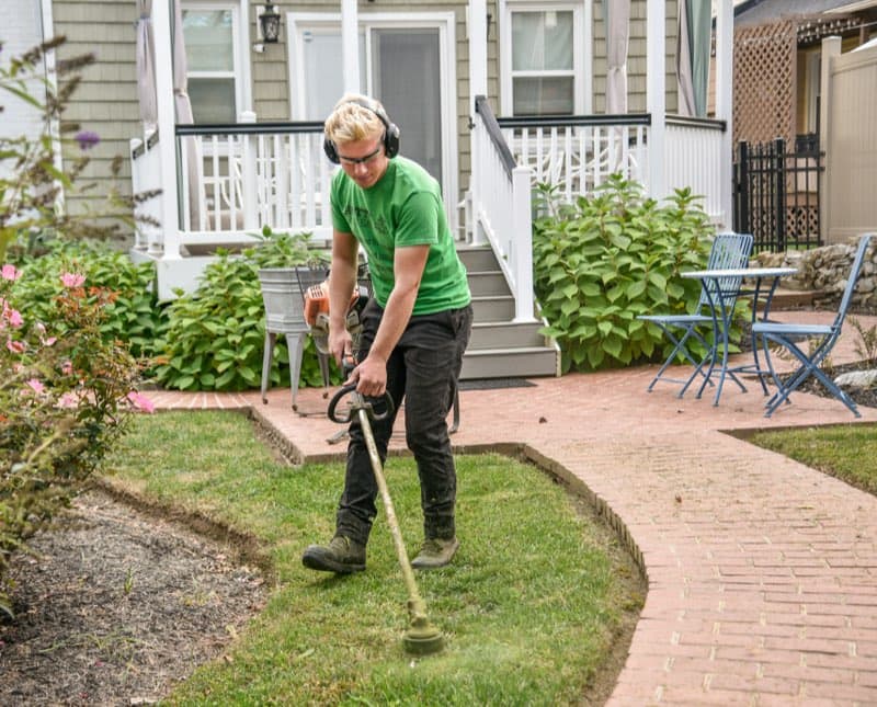 Gardener strimming the edge of a lawn
