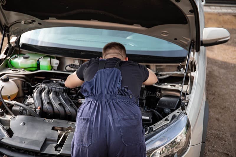 Mechanic leaning under an open bonnet to work on the engine