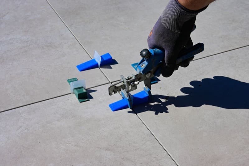 Gloved hand using a levelling tool on newly laid tiles